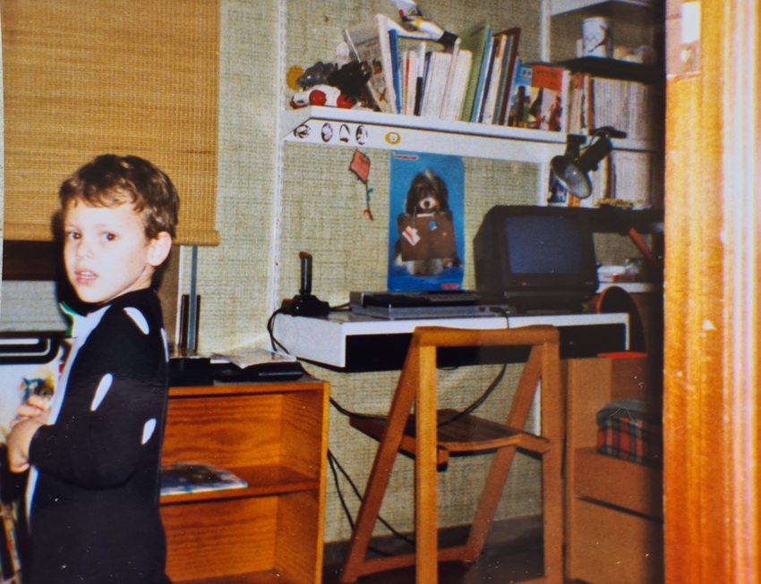 A little kid dressed in a cat costume in front of an MSX computer